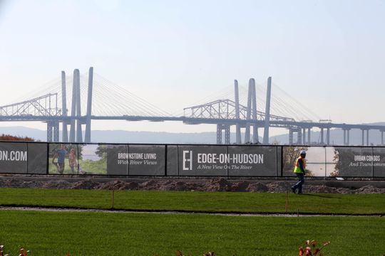 A worker walks past banners for the Edge-on-Hudson, a new residential development planned for the site of the former General Motors assembly plant in Sleepy Hollow Oct. 23, 2018. Construction of townhomes at the site has begun. Infrastructure work, the planting of grass, as well as pile driving for foundations is under way.